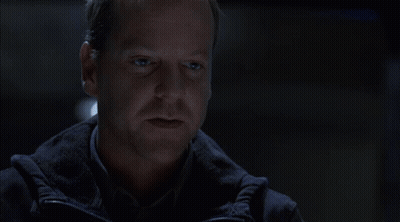 Man And Woman Sitting At Table In Dark Room Talking GIF