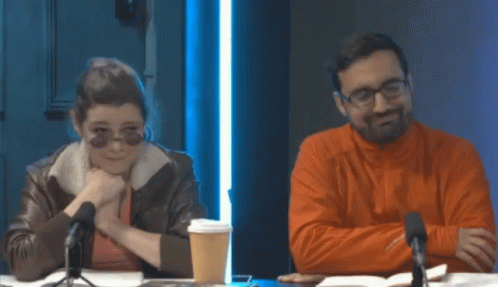 Man And Woman Sitting At Table With Microphones GIF
