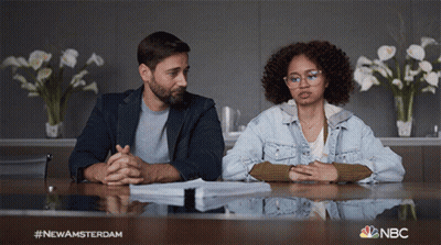 Man And Woman Sitting At Table With NBC Logo GIF