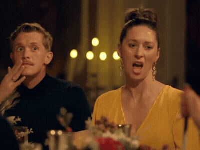 Man And Woman Sitting At Table Woman In Yellow Dress And Earrings GIF