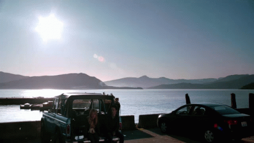 Man and Woman Sitting in Back of Truck Near Lake