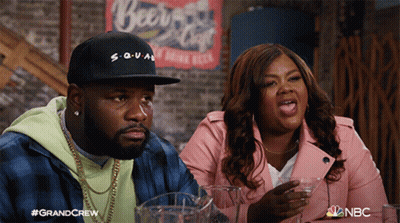 Man And Woman Sitting In Front Of Beer Sign GIF