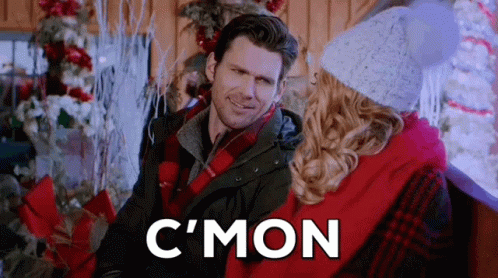 Man And Woman Sitting Next To Christmas Tree Smiling GIF
