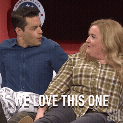 Man And Woman Sitting Next To Each Other Saying We Love This One GIF