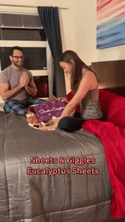 Man And Woman Sitting On Bed Giggling GIF