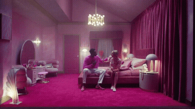 Man And Woman Sitting On Bed In Pink Room GIF