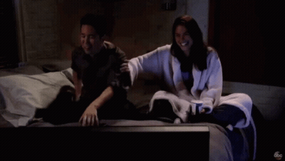 Man And Woman Sitting On Bed Watching TV With ABC Logo GIF