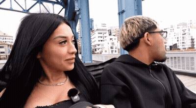 Man And Woman Sitting On Bridge With EP Necklace GIF