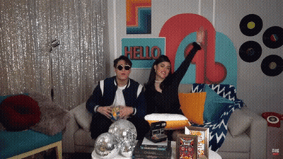 Man And Woman Sitting On Couch Before Hello Wall GIF