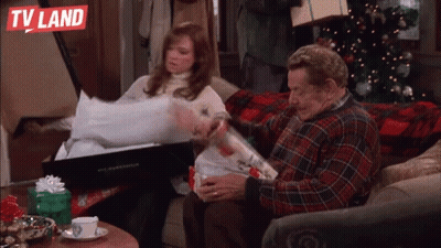 Man And Woman Sitting On Couch In Front Of Christmas Tree And TV Land Logo GIF