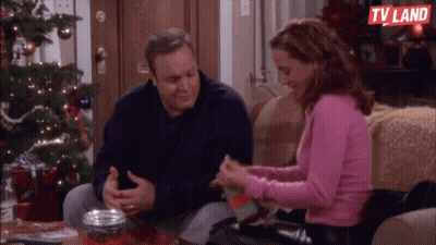 Man And Woman Sitting On Couch Near Christmas Tree GIF