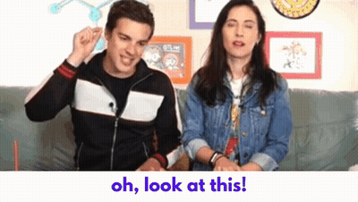 Man And Woman Sitting On Couch Saying Oh Look At This GIF