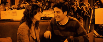 Man And Woman Sitting On Couch Smiling At Each Other GIF