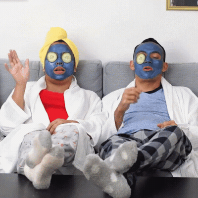 Man And Woman Sitting On Couch With Face Masks GIF