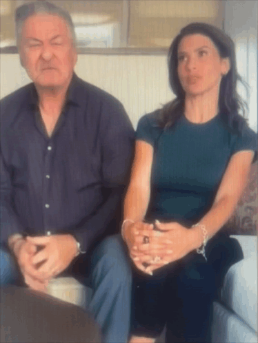 Man And Woman Sitting On Couch With Hands Folded GIF