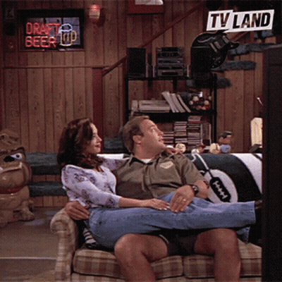 Man And Woman Sitting On Couch With TV Land Sign GIF