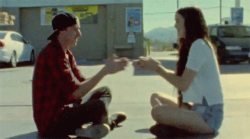 Man And Woman Sitting On Ground Holding Hands GIF