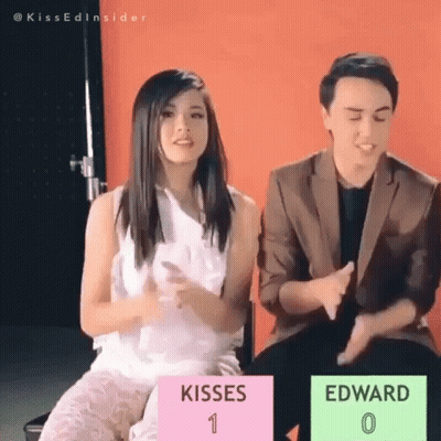 Man And Woman Sitting With Sign Kisses 1 Edward 0 GIF