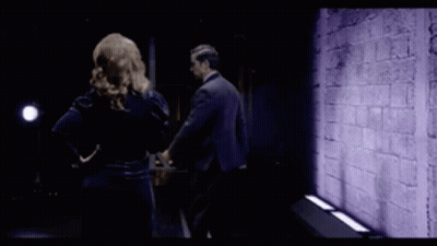 Man And Woman Standing Before Purple Wall GIF