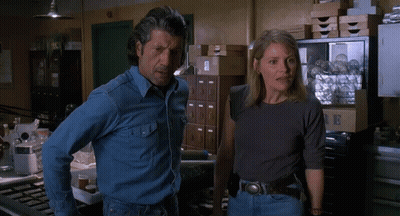 Man And Woman Standing Beside Cabinet With Letter B GIF