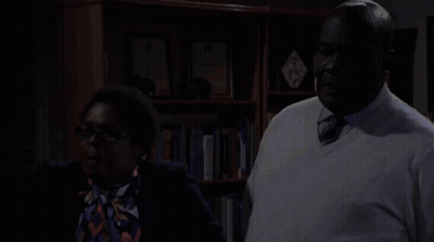 Man And Woman Standing In Front Of Bookshelf GIF