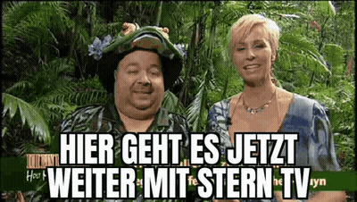 Man and Woman Standing in Front of Hier Geht Es Jetzt Sign