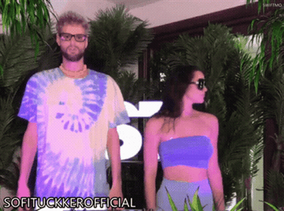 Man And Woman Standing In Front Of Softtuckkerofficial Sign GIF
