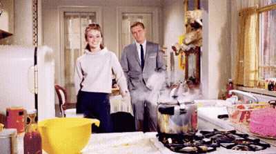 Man And Woman Standing In Kitchen Near Boiling Pot GIF