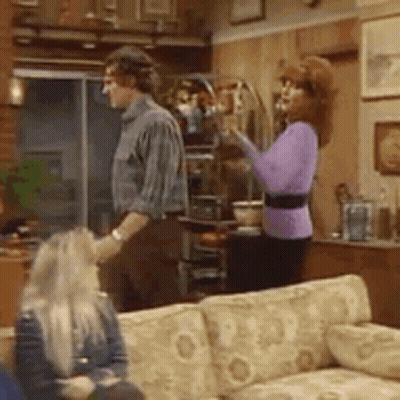 Man And Woman Standing In Living Room With Couch GIF