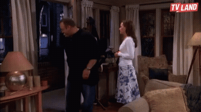 Man And Woman Standing In Living Room With TV Land Logo GIF