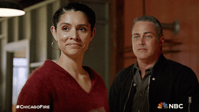 Man And Woman Standing Next To Chicago Fire Advertisement GIF