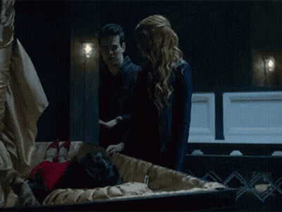 Man And Woman Standing Next To Coffin With Woman Inside GIF
