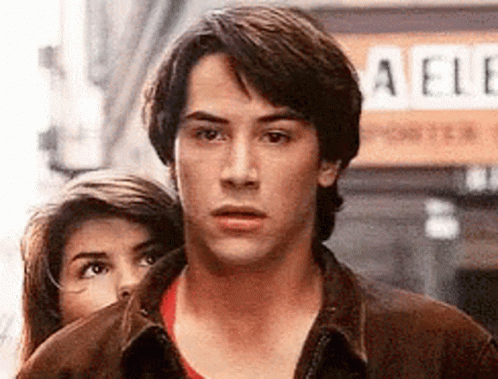 Man And Woman Standing Next To Each Other In Front Of Aelle Sign GIF