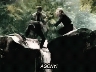 Man And Woman Standing On Rock In Waterfall GIF