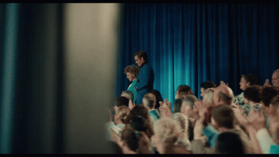 Man And Woman Standing On Stage In Front Of Crowd GIF
