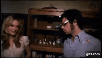 Man And Woman Talking By Bookshelf GIF