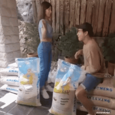 Man And Woman Talking Next To Rice Bags GIF