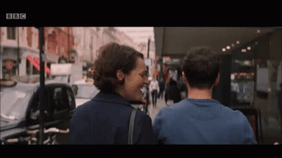 Man And Woman Walking Down Street With BBC Logo GIF