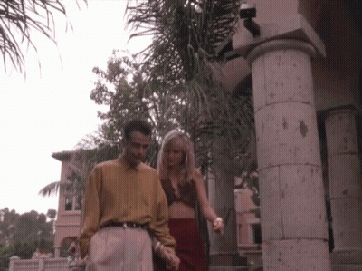 Man And Woman Walking Hand In Hand In Front Of Building GIF