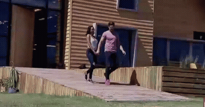 Man And Woman Walking In Front Of Building GIF