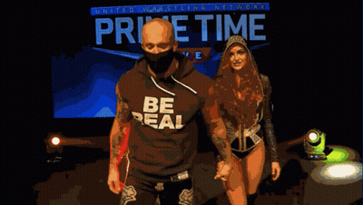 Man And Woman Walking In Front Of Home Time Live Sign GIF