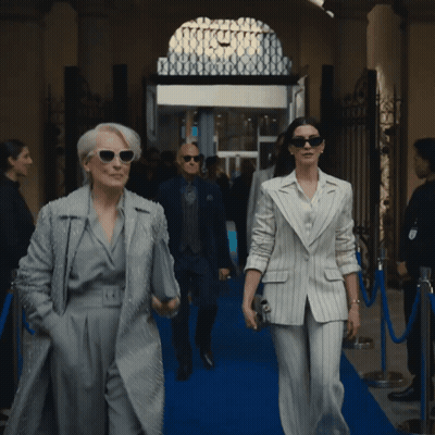 Man And Woman Walking On Blue Carpet In Front Of Building GIF