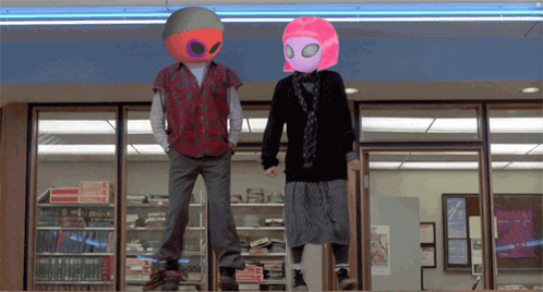 Man And Woman Wearing Alien Masks In Front Of Book Store GIF