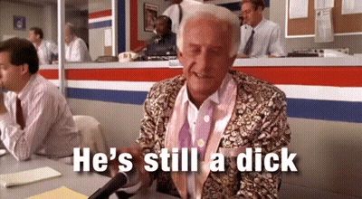 Man At Desk With Mic Saying He's Still A Dick GIF