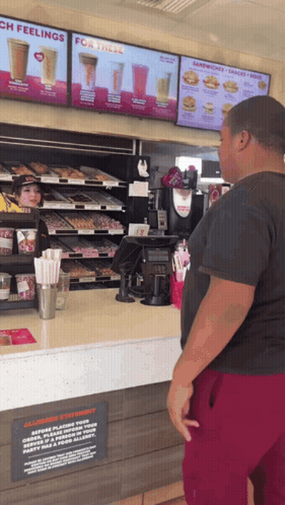 Man At Dunkin Donuts Counter Looking At Menu GIF
