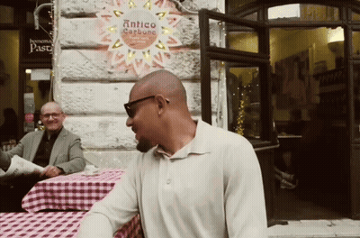 Man At Table In Front Of Antico Carbone Sign GIF