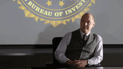 Man At Table In Front Of Bureau Of Invest Screen GIF