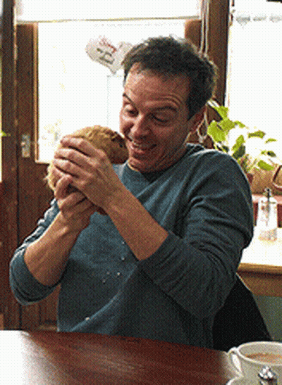 Man At Table With Coffee And 'Ee' Sign GIF