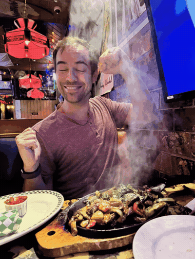 Man At Table With Food And Chuck E Cheese Sign GIF