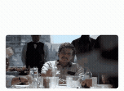 Man At Table With Glasses And Alcohol Bottles GIF